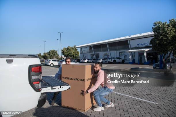 two men lifting a new appliance into a car. - picking up groceries stock pictures, royalty-free photos & images