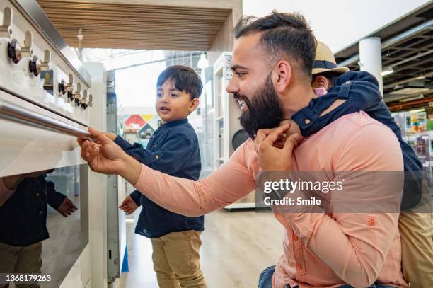 a father and two sons looking at ovens in an appliance store. - new dad stock-fotos und bilder