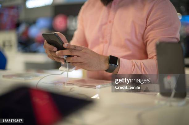 man testing a new mobile phone. part of a series. - fake smile stock-fotos und bilder