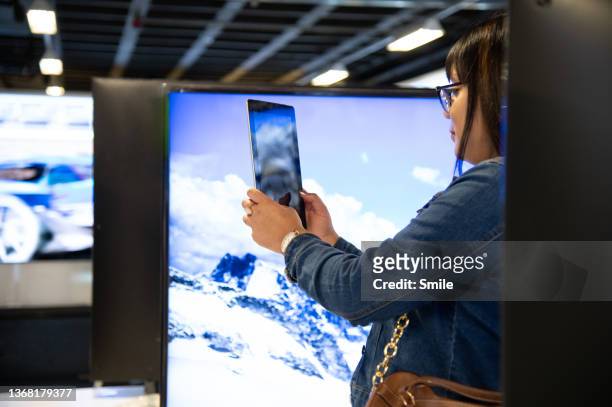 a profile of a woman looking at her tablet screen. - mall home appliance stock pictures, royalty-free photos & images