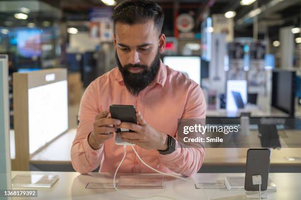 a young man testing out a mobile phone in a store. - electronic products stock pictures, royalty-free photos & images