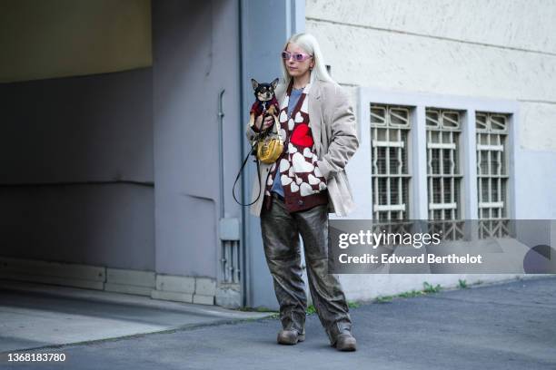 Guest wears gold / red / silver rings, a silver pearls necklace, a gray t-shirt, a brown with white latte heart print pattern oversized cardigan, a...