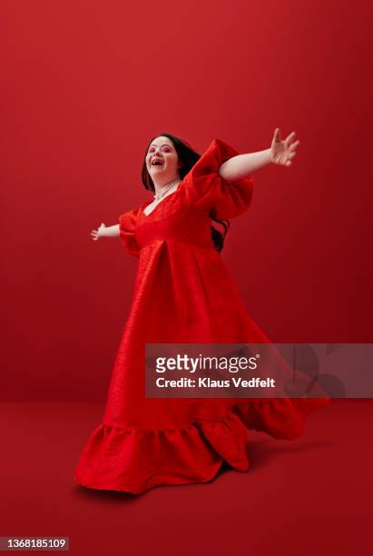 Cheerful woman with arms outstretched against red background