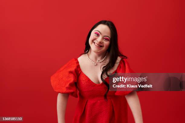 smiling woman wearing pearl necklace against red background - body positive stockfoto's en -beelden