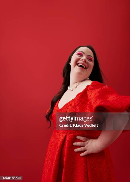 young woman with hand on hip against red background - cosmetics isolated stock pictures, royalty-free photos & images