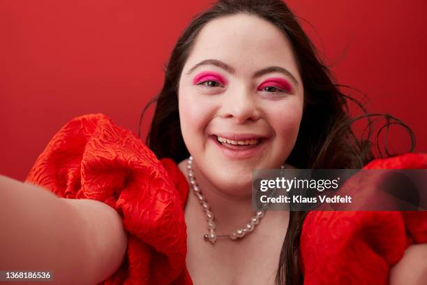 smiling woman taking selfie against red background - woman selfie stockfoto's en -beelden