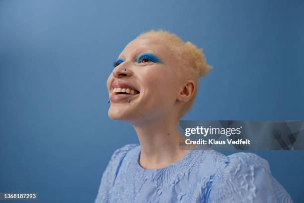 happy albino woman against blue background - black color photos et images de collection