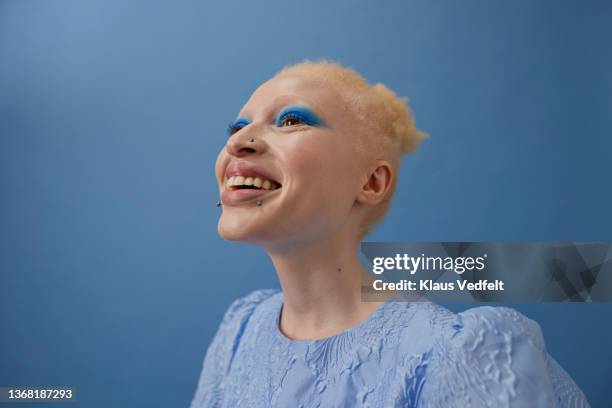 happy albino woman against blue background - make up stock pictures, royalty-free photos & images