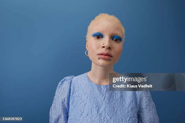 serious albino woman against blue background - albino stock-fotos und bilder