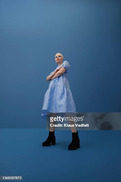 albino woman with arms crossed against blue background - blue dress fotografías e imágenes de stock