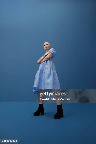 albino woman with arms crossed against blue background - blue shoe foto e immagini stock