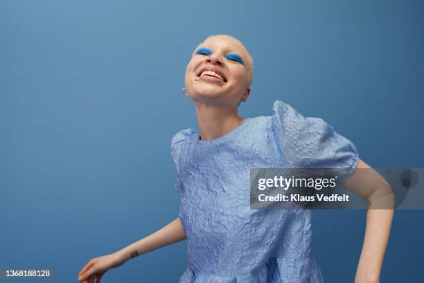 happy albino woman dancing against blue background - black makeup stockfoto's en -beelden