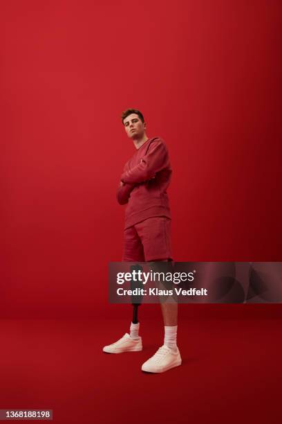 young man with artificial limb standing with arms crossed - red shorts stock pictures, royalty-free photos & images