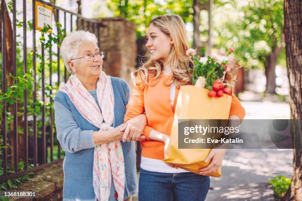 une petite-fille souriante fait du shopping pour sa grand-mère - assistant photos et images de collection