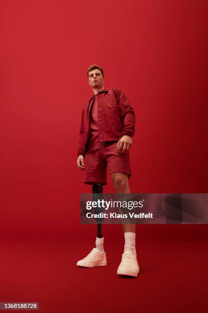 man with artificial limb against red background - toughness stock-fotos und bilder