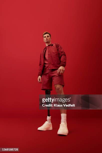 man with artificial limb against red background - low angle view imagens e fotografias de stock