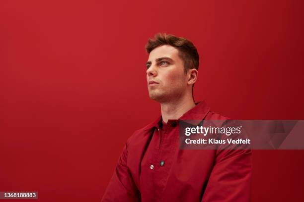 man with brown hair against red background - red shirt stockfoto's en -beelden