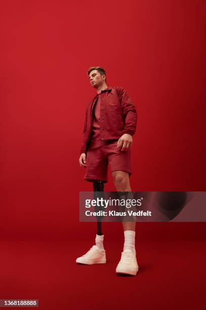 Man looking away while standing against red background
