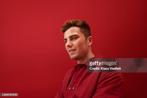 smiling young man against red background - red jacket stock pictures, royalty-free photos & images