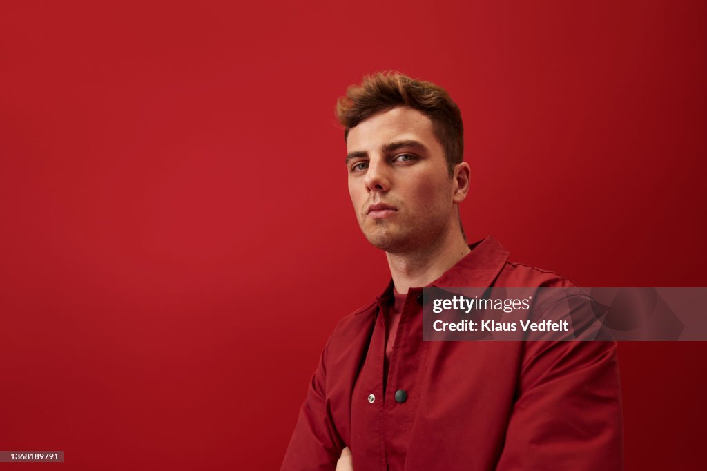 Portrait of young man against red background