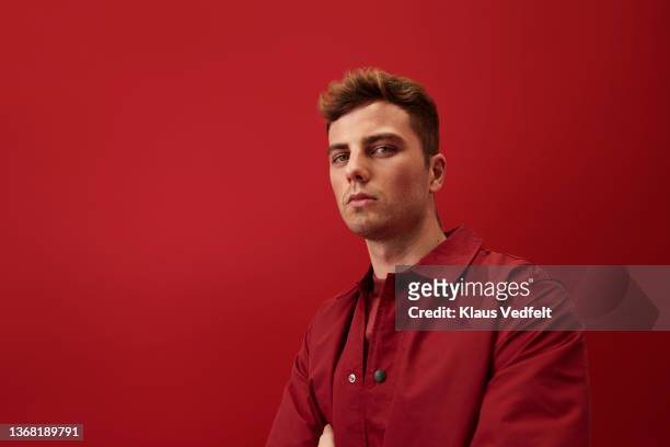 portrait of young man against red background - kopfbild stock-fotos und bilder
