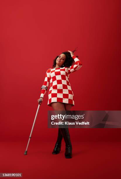 woman with hand in hair against red background - portrait casual woman background studio stockfoto's en -beelden