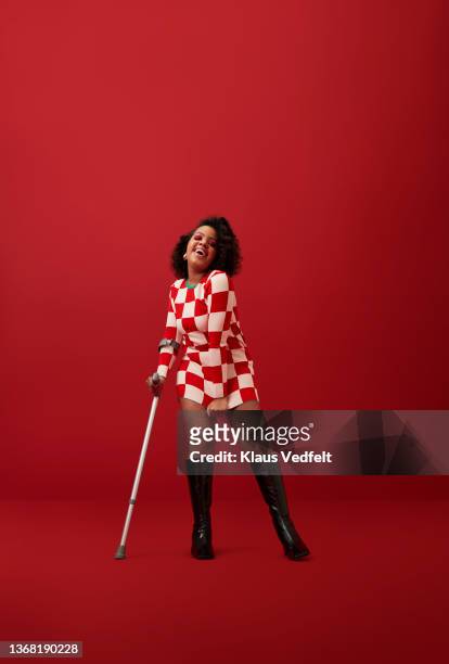 Cheerful woman in checked dress against red background