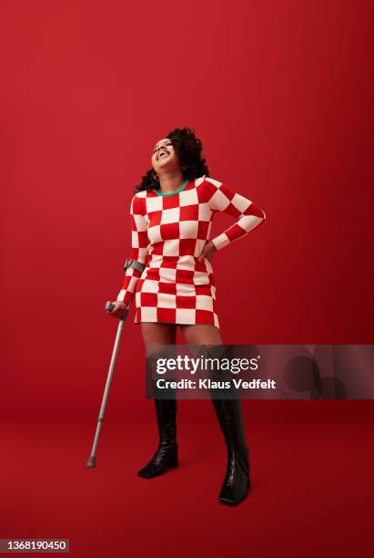 woman with crutch laughing against red background - visual impairment - fotografias e filmes do acervo