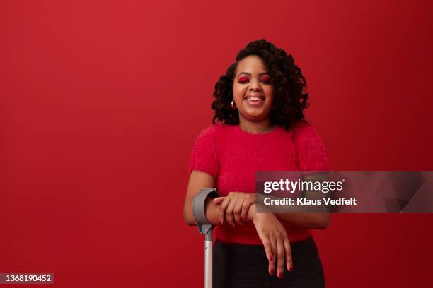 happy curly haired woman against red background - disabled person photos et images de collection