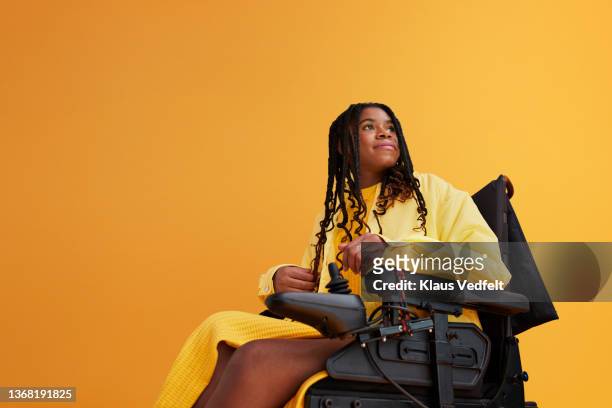 young woman with braided hair sitting in wheelchair - personal injury fotografías e imágenes de stock