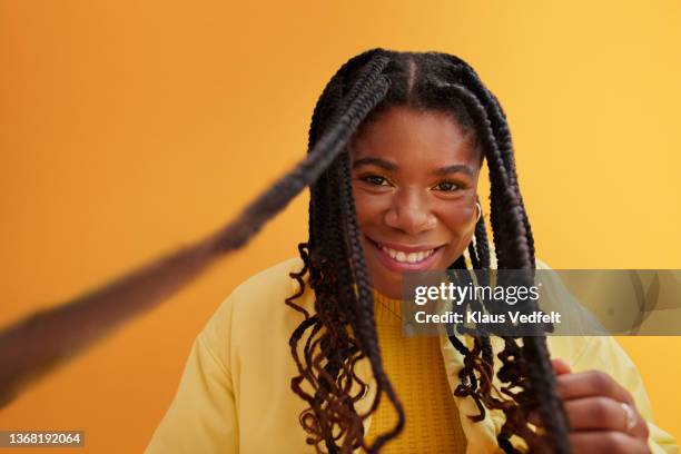 happy woman with braided hair against yellow background - studio series stock-fotos und bilder