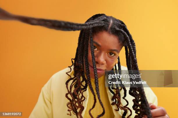 woman with braided hair against yellow background - braid hairstyle stock pictures, royalty-free photos & images