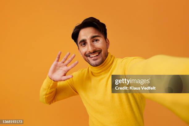 happy man with vitiligo waving hand against yellow background - zwaaien stockfoto's en -beelden
