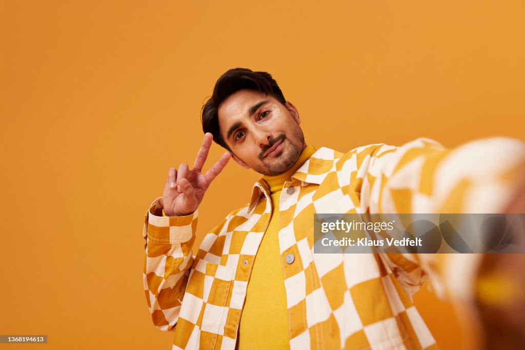 Young man with vitiligo gesturing peace sign
