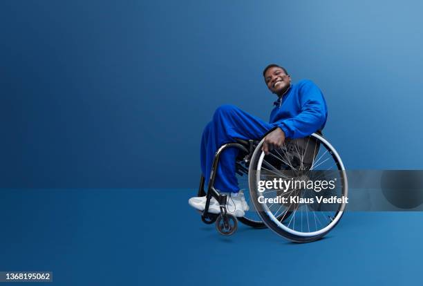 man with disability in tracksuit sitting in wheelchair - man in wheelchair stock pictures, royalty-free photos & images