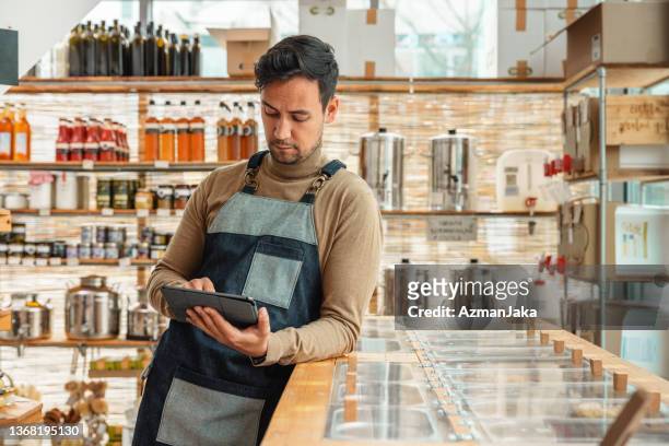 male employee using a digital tablet in a zero waste store - deli counter stock pictures, royalty-free photos & images