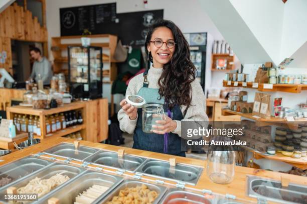 photo of a smiling female employee in a sustainable store holding a jar - plastfritt bildbanksfoton och bilder