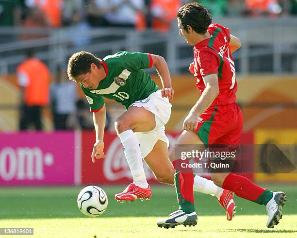 Guillermo Franco of Mexico puts his head down and speeds away from Andranik Teymourian of Iran in sold-out Franken stadium, Nuremberg, Germany on...