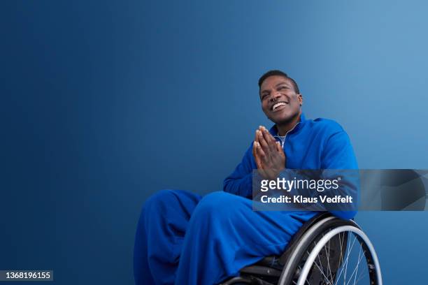 happy man with disability sitting with hands clasped - colour image stock-fotos und bilder