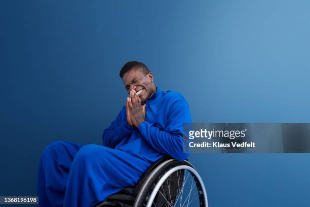Happy man with disability sitting with hands clasped in wheelchair