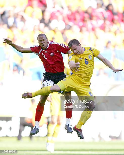 The ball is jammed between Densil Theobald of Trinidad & Tobago and Tobias Linderoth of Sweden during the Group B match in Dortmund, Germany on June...