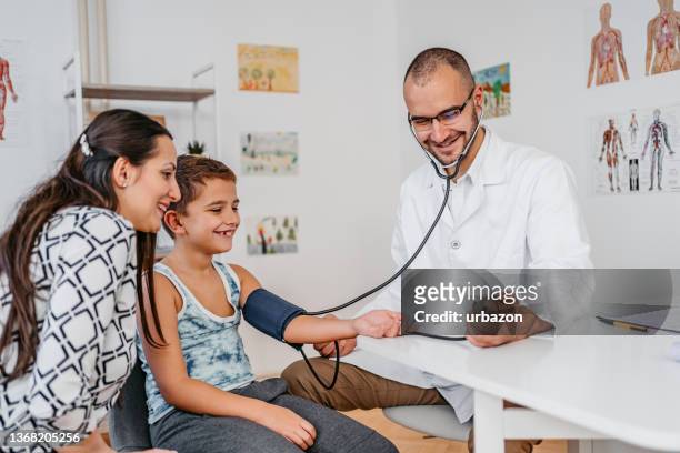 kinderarzt misst blutdruck eines kinderpatienten - hypertension stock-fotos und bilder
