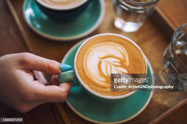 woman holding a cup of cafe latte in cafe. - coffee art stockfoto's en -beelden