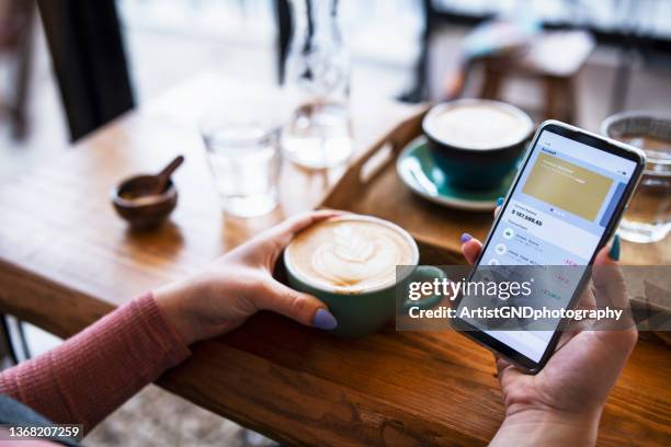 foto de una mujer joven administrando una cuenta bancaria en un teléfono inteligente en el café. - banca electrónica fotografías e imágenes de stock