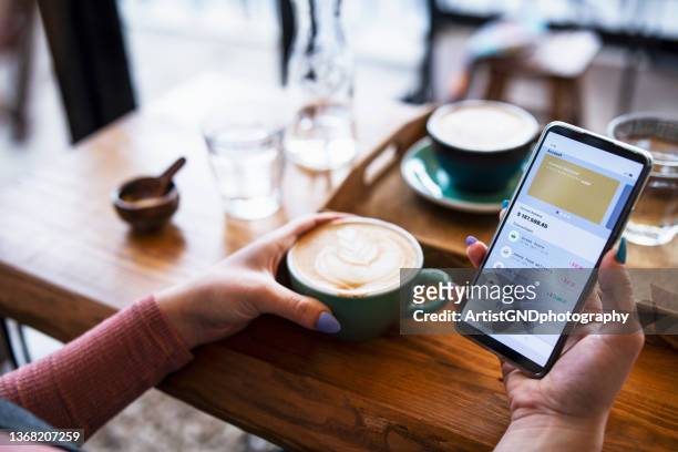 shot of young woman managing bank account on smartphone at cafe. - screen closeup stock pictures, royalty-free photos & images
