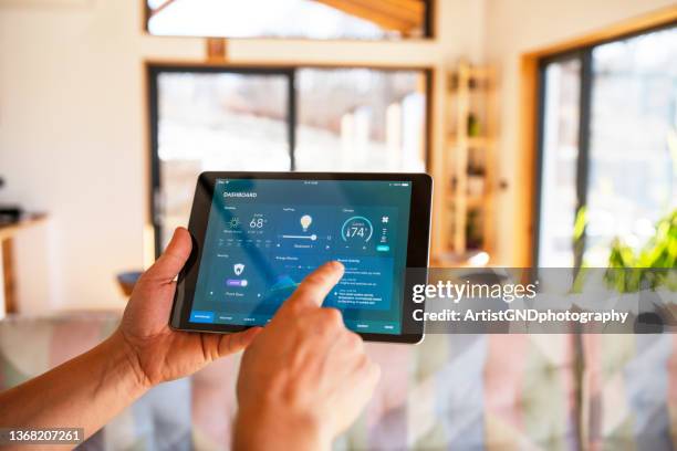 mann mit tablet mit smart-home-steuerungsfunktionen zu hause. - internet of things stock-fotos und bilder