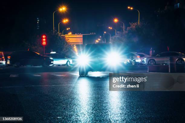 illuminated headlights on street at night - faro luz de vehículo fotografías e imágenes de stock