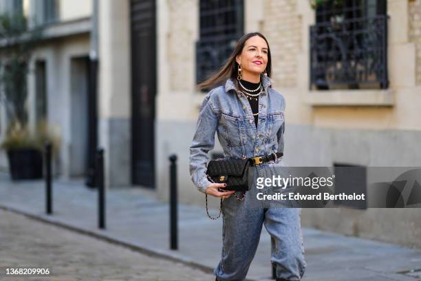 Alba Garavito Torre wears a black turtleneck pullover, gold and pearls large pendant earrings, white pearls necklaces, a blue faded denim buttoned...