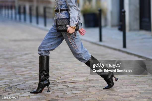 Alba Garavito Torre wears a blue faded denim buttoned jumpsuit from Mango, a black shiny leather gold buckle Triomphe belt from Celine, gold...