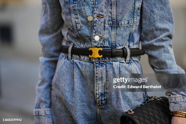 Alba Garavito Torre wears a blue faded denim buttoned jumpsuit from Mango, a black shiny leather gold buckle Triomphe belt from Celine, gold...